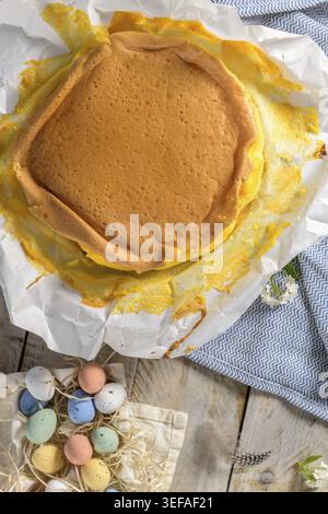 Portuguese sponge cake wrapped in the typical paper used on the baking, on wooden background with painted easter eggs decoration Stock Photo