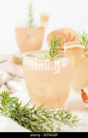 Grapefruit juice with rosemary in glasses on the table. Refreshing summer cocktail Stock Photo