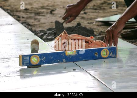 Worker Installing Floor Tiles Using Spirit Level During Home Construction and Renovation Process Stock Photo
