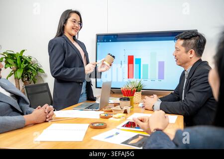 A team of business professionals discussing project details during a formal presentation in a modern office meeting room. Stock Photo