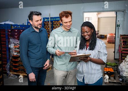 Warehouse workers collaborating on inventory management using digital tablet Stock Photo