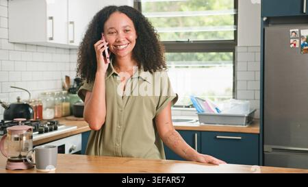 Smiling Woman Talking On Phone In Modern Kitchen With Coffee Mug And Casual Style Stock Photo