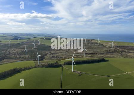 Aerial view of a windfarm with white turbines scattered across rolling green hills under a blue sky with wispy clouds Scotland, United Kingdom. Stock Photo
