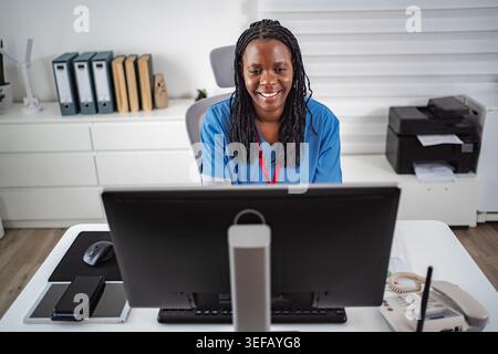 Female medical professional smiling while working on computer Stock Photo