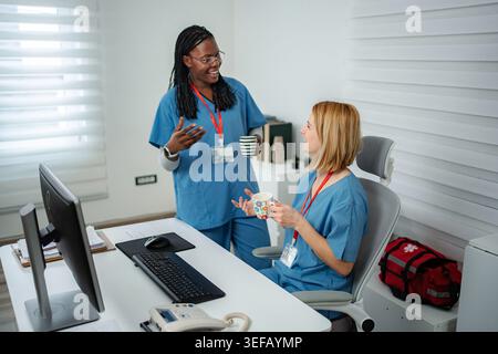Diverse nurses collaborating and discussing in hospital office during break Stock Photo