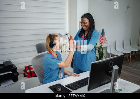Medical workers high fiving, celebrating achievement in a hospital office Stock Photo