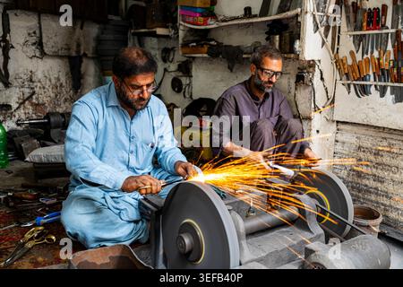 Blacksmiths shaping metal and working with tools in Lahore’s old town during daylight hours Stock Photo