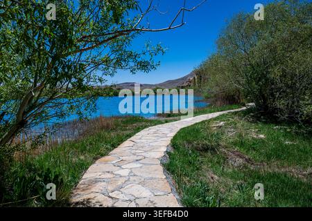 Explore multi coloured lakes in Band-e-Amir National Park while walking on a stone path among trees and grass in Afghanistan Stock Photo