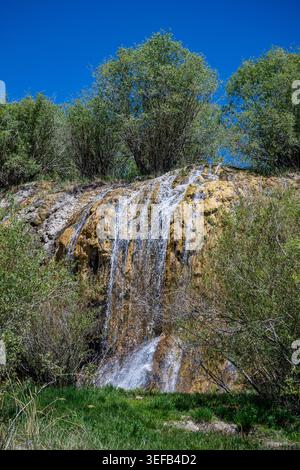 Waterfall flowing down rocks in Band-e-Amir National Park during bright sunlight in Afghanistan Stock Photo
