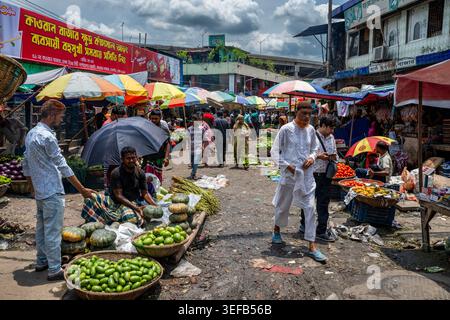 Vegetable sellers and buyers at market in Dhaka during busy day with colorful umbrellas Stock Photo