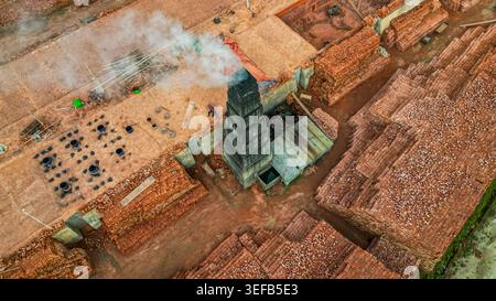 Brick production process taking place at a factory with stacked bricks and a chimney in Bangladesh Stock Photo