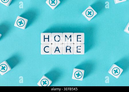 Home care concept with letter blocks and medical cross icons on blue background Stock Photo