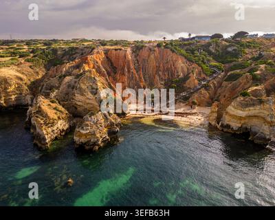 Sunset over beach cliffs with rocky shoreline in Algarve region of Portugal Stock Photo
