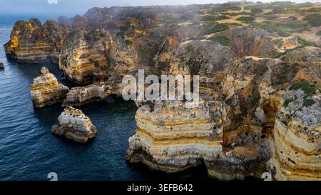 Sunset view of beach cliffs with ocean waves in Algarve region of Portugal near Lagos city Stock Photo