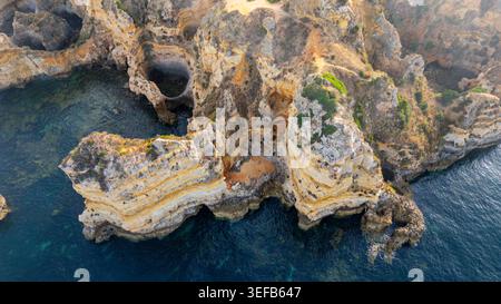 Sunset over beach cliffs showing waves and rocks along the coast in Algarve Portugal Stock Photo