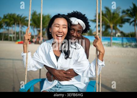 Happy young couple embracing and laughing on a tropical beach during summer vacation Stock Photo
