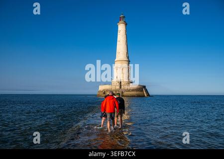 Visitors walk on the sand around the lighthouse of Cordouan during low tide in France Stock Photo