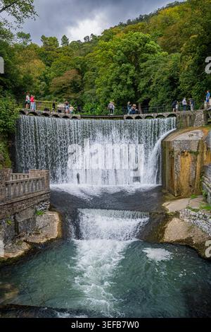 Waterfall flows over artificial rocks with people enjoying the view near New Athon Stock Photo