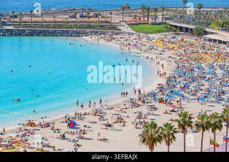 Visitors enjoy sun and beach activities at Amadores beach in Gran Canaria on a sunny day in the Canary Islands Stock Photo
