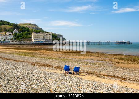 Couple enjoys sunny day on Llandudno beach with pier and landscape in background, Conwy, Wales Stock Photo