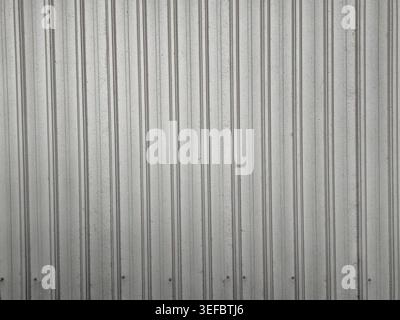 A close-up, front-facing view of a gray corrugated metal wall with vertical ridges and visible fasteners. Stock Photo