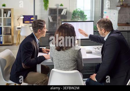 Business team analyzing data on computer monitor during office meeting discussion Stock Photo