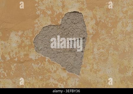 arge central area of stucco has fallen away to reveal raw grey masonry. The remaining yellow paint features a distressed texture with multiple cracks. Stock Photo