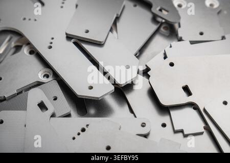 dense pile displays numerous thin, precision-cut carbon fiber composite parts scattered randomly, used as structural plates for high-performance FPV d Stock Photo