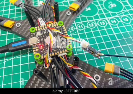 An assembled sport FPV drone body with a stack flight controller and DIY USB-flashed electronic speed controller is ready for flight . Close-up Stock Photo