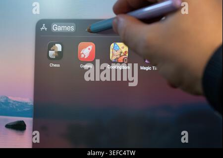 New York, USA - May 14, 2026: Selecting computer games app on screen menu pointing with pencil  close up view Stock Photo