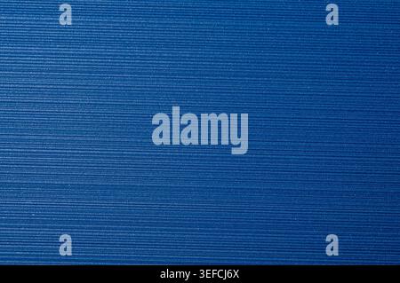 A close-up view of a textured surface in a rich blue hue, featuring uniform horizontal striations that form a repeating pattern Stock Photo