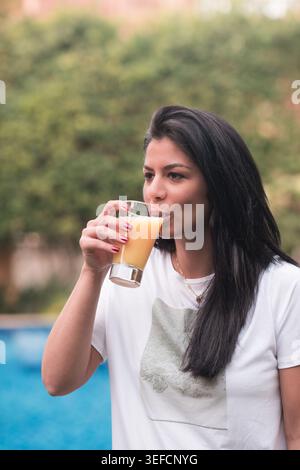 Middle Eastern woman enjoying orange juice by the pool during Ramadan iftar at a modern home Stock Photo
