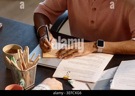 Black Man Writing Note during Business Meeting and Document Review Stock Photo