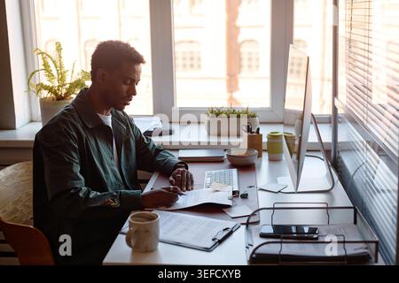 Black Man Reviewing Documents at Desk for Office Administration Stock Photo