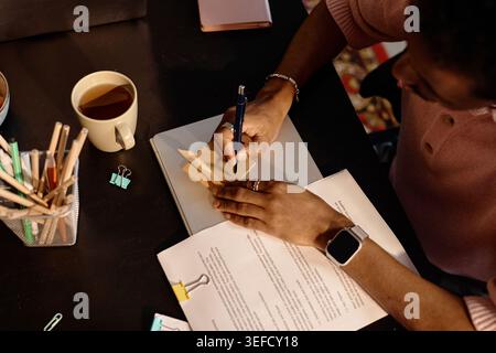 Black Man Writing Reminder on Sticky Note at Desk for Business Planning Stock Photo