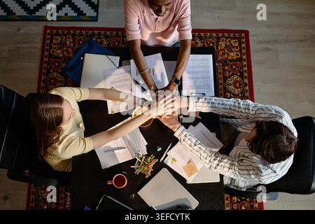 Diverse Business Team Joining Hands in Workplace Collaboration Stock Photo