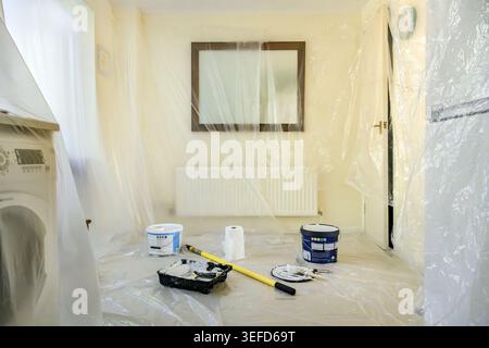 Kitchen and Dining room prepared for painting with walls, units and white goods covered in clear protective plastic sheeting Stock Photo
