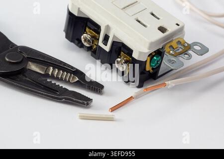 Close-up of electrical outlets, screwdriver, and wire stripper tools on a white background, illustrating electrical installation, home wiring, mainten Stock Photo