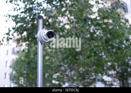 Security surveillance camera is installed on a metal pole in a public residential area. Stock Photo