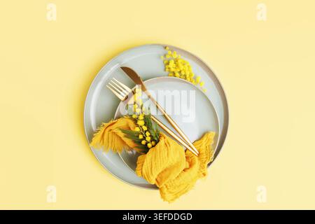 Modern spring composition with mimosa branch and yellow napkin Stock Photo