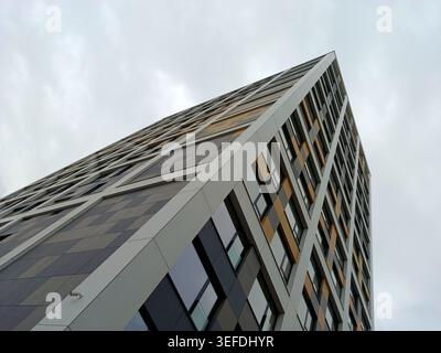 Modern residential tower featuring a striking pattern of square and rectangle windows and panels, creating a dynamic, geometric facade under an overca Stock Photo