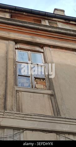 Old building facade with a weathered, partially bricked up window of mixed terracotta and pale bricks, showing decay, repair and layered textures of a Stock Photo