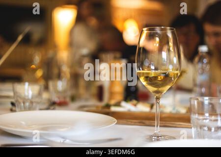 Restaurant atmosphere. A glass of white wine on a set table. Stock Photo