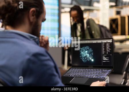 Professional man working with artificial intelligence software on laptop in airport lounge, exploring deep learning models and autonomous systems. Global business travel scene with AI innovation. Stock Photo