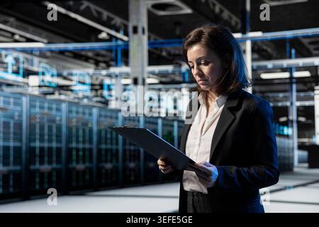 Server farm manager looking over system benchmarks results after doing wireframe mesh mapping with augmented reality. Data center specialist reading infrastructure digital twin scan results documents Stock Photo