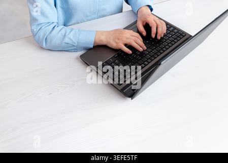 Top view of hands typing on laptop keyboard in clean workspace with large copy space, suitable for business, coding and productivity concepts Stock Photo