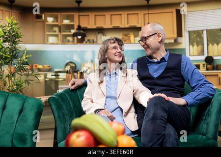 Romantic couple, smiling at each other, peaceful moment, retirement at home, husband and wife, safety and emotional support, independence, in-home wellness, companionship in old age. Stock Photo