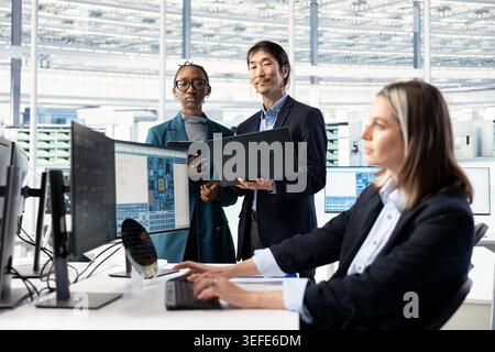 Portrait of smiling man and coworkers doing semiconductors prototyping in office, brainstorming. Happy senior manager and engineers collaborating on technical innovations in microchip factory RD lab Stock Photo