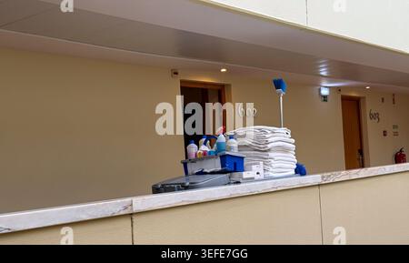 housekeeping cart with cleaning products and fresh towels in hotel corridor Stock Photo