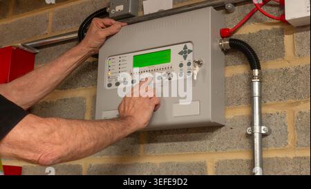 Fire alarm engineer investigating a fault on a fire protection system during planned maintenance, ensuring the safe and reliable operation of industri Stock Photo